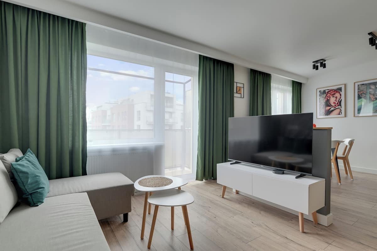 A modern living room with a sofa, TV, and two small tables.