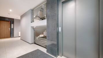 A modern interior with a glass elevator, a wooden door, and a grey carpet.