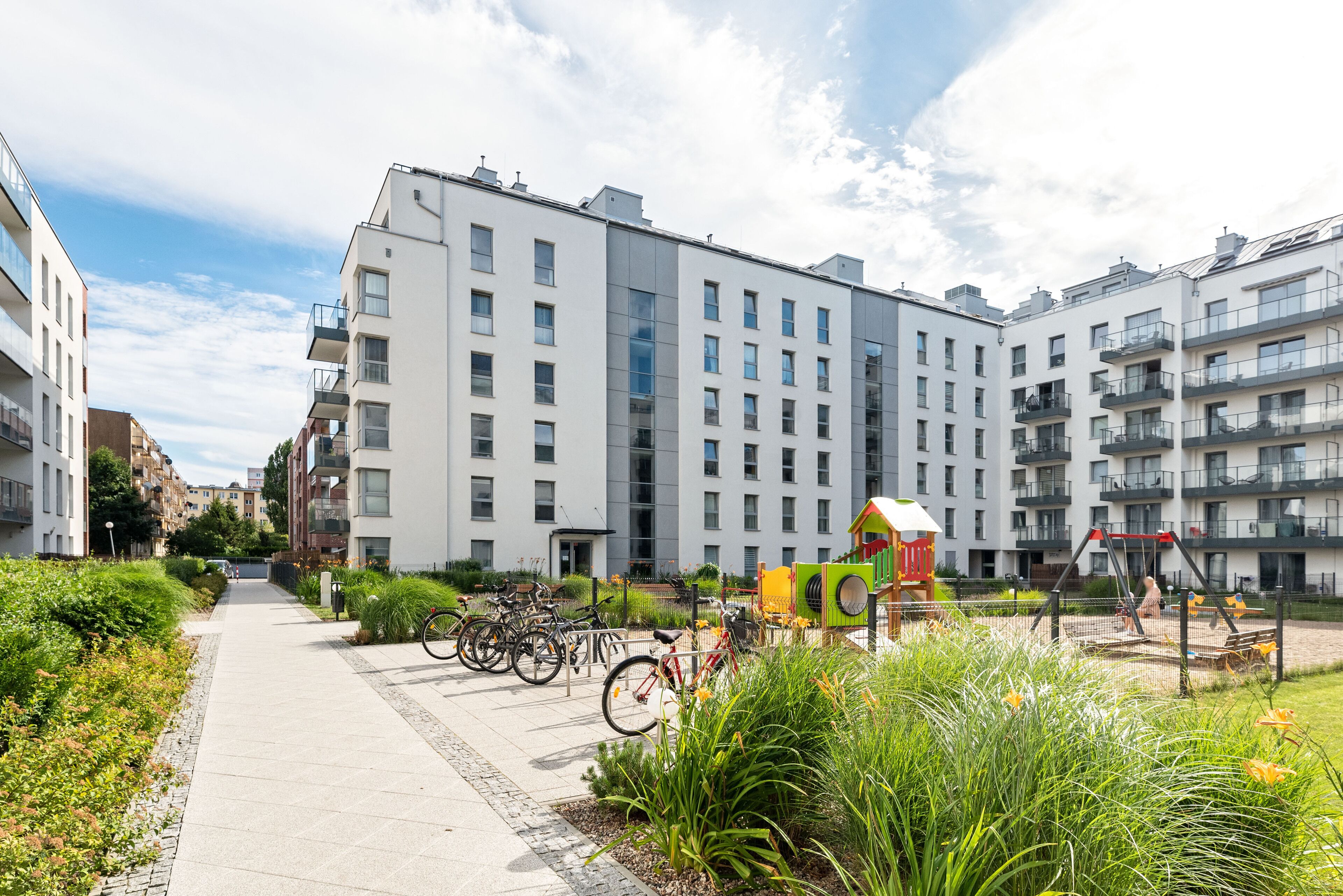 A modern apartment building with a central courtyard, bicycles, and a playground.