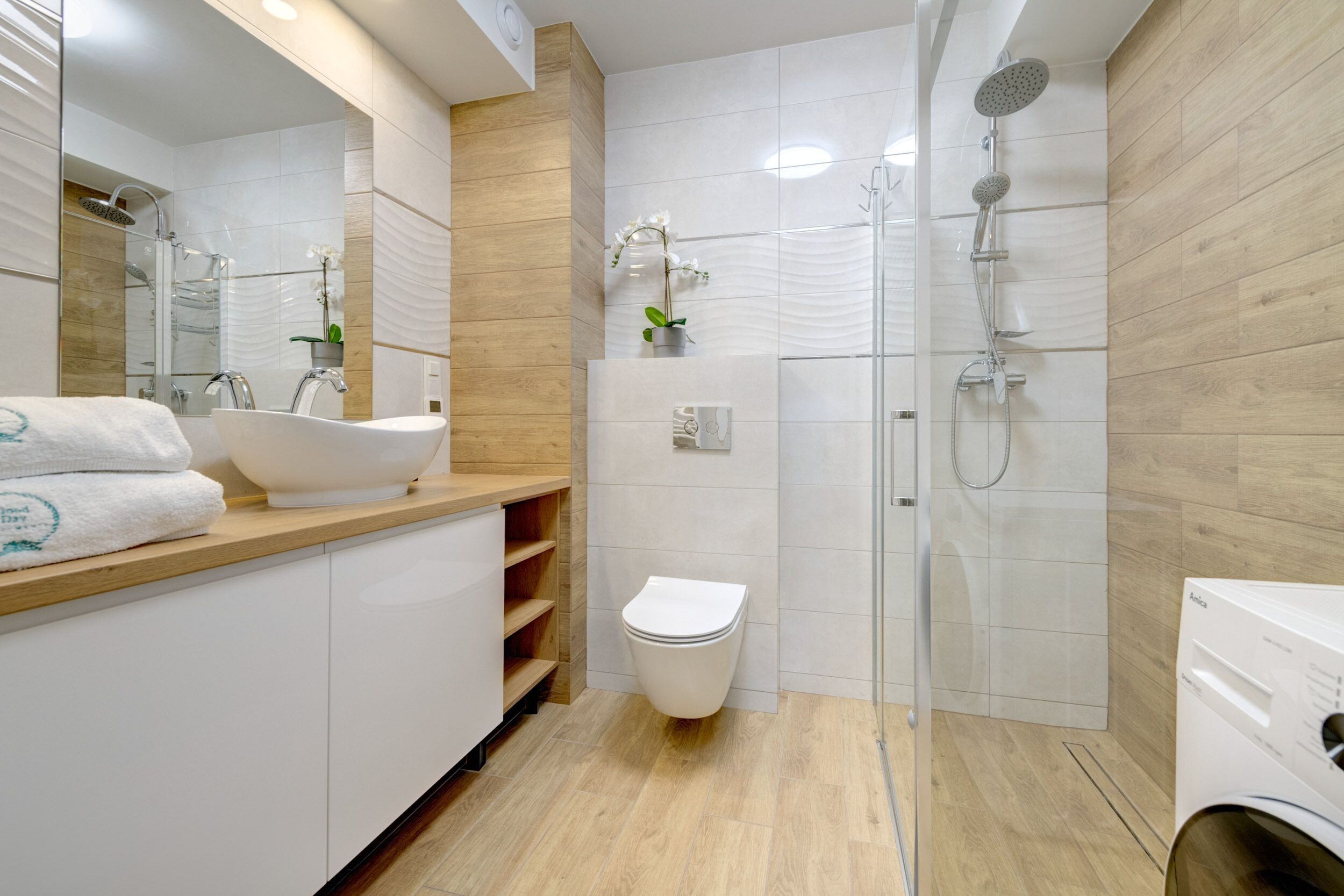 Une salle de bain moderne avec un lavabo sur pied, des toilettes et une douche à l’italienne.