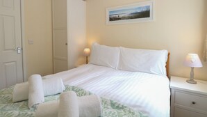 A bedroom with a bed, two bedside lamps, a nightstand, a wardrobe, and a framed picture on the wall. - 14 The Dell (Norwich)