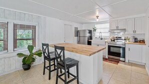 Una cocina moderna con armarios blancos, una isla de madera y un horno empotrado.