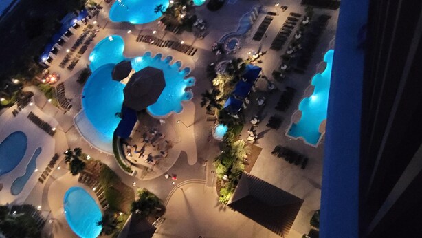 Een luchtbeeld van een resort met meerdere zwembaden, loungegedeeltes en een centraal, rond zitgedeelte.
