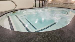 Un bain à remous avec un mur en pierre et un sol carrelé.