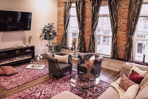 A living room with a fireplace, a television, and a large window with curtains.