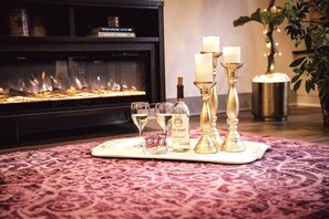 Une pièce chaleureuse avec une cheminée, un plateau avec des verres, une bouteille et des bougies.
