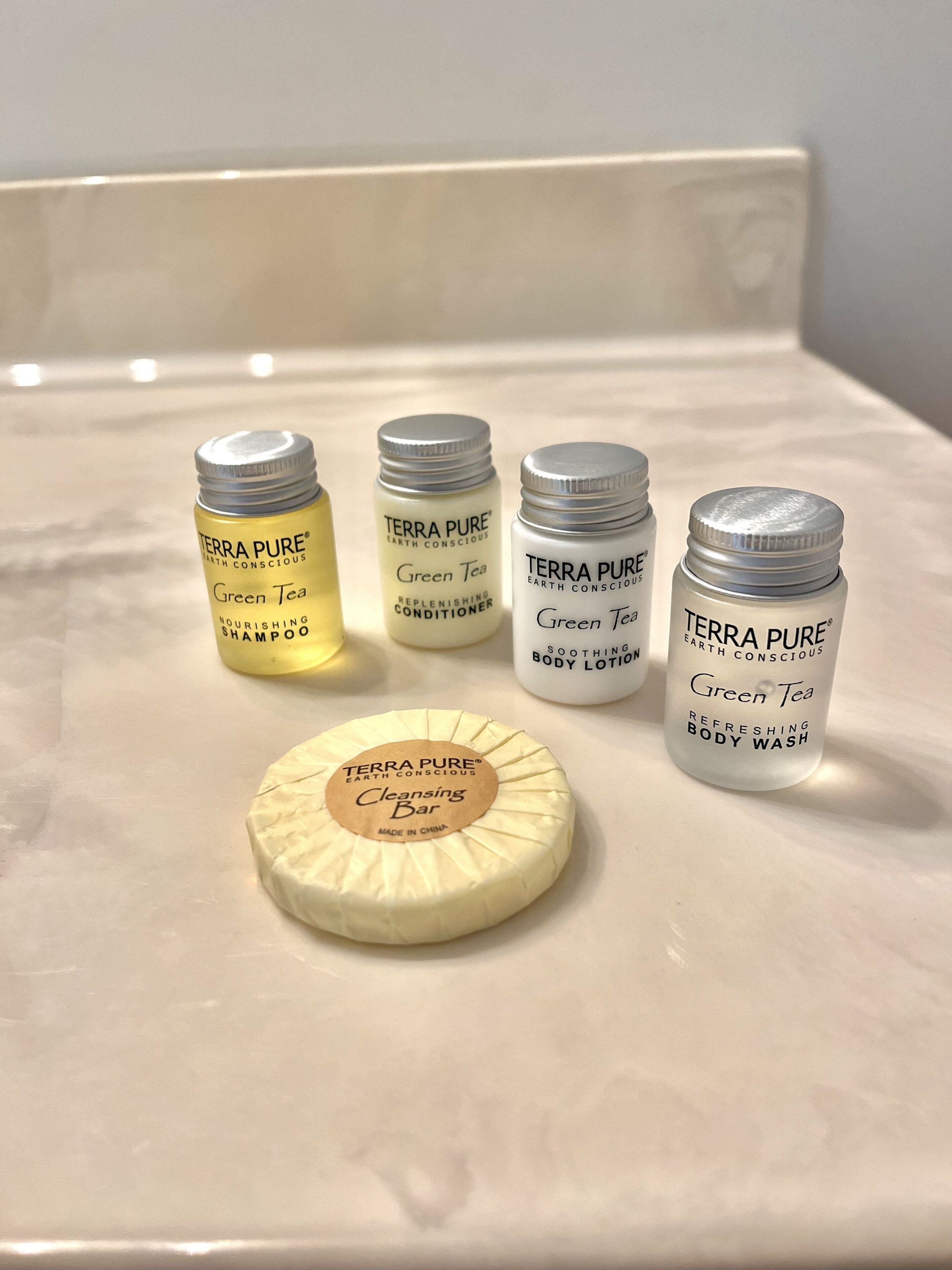 Un ripiano del bagno con cinque flaconi di prodotti Terra Pure Earth Conscious e una saponetta detergente.