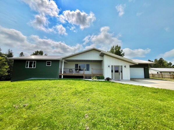 A two-story house with a front porch, a garage, and a well-maintained lawn. - Kountry Home With Gorgeous Sunset Views (Menahga)