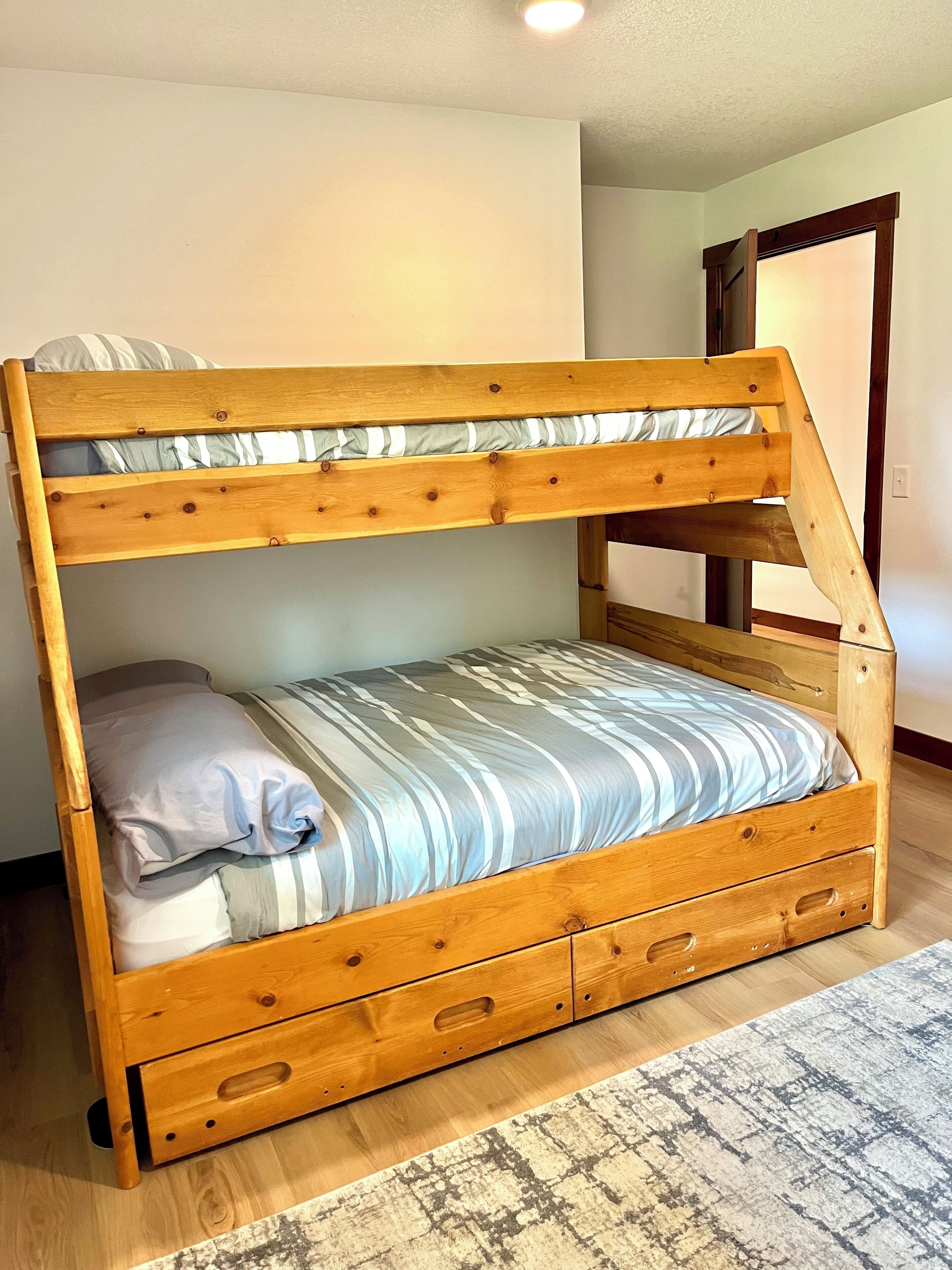 A bunk bed with two levels, each with a pillow and a striped blanket.