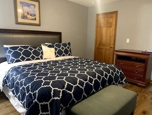 Une chambre à coucher avec un grand lit, une commode en bois et une porte.