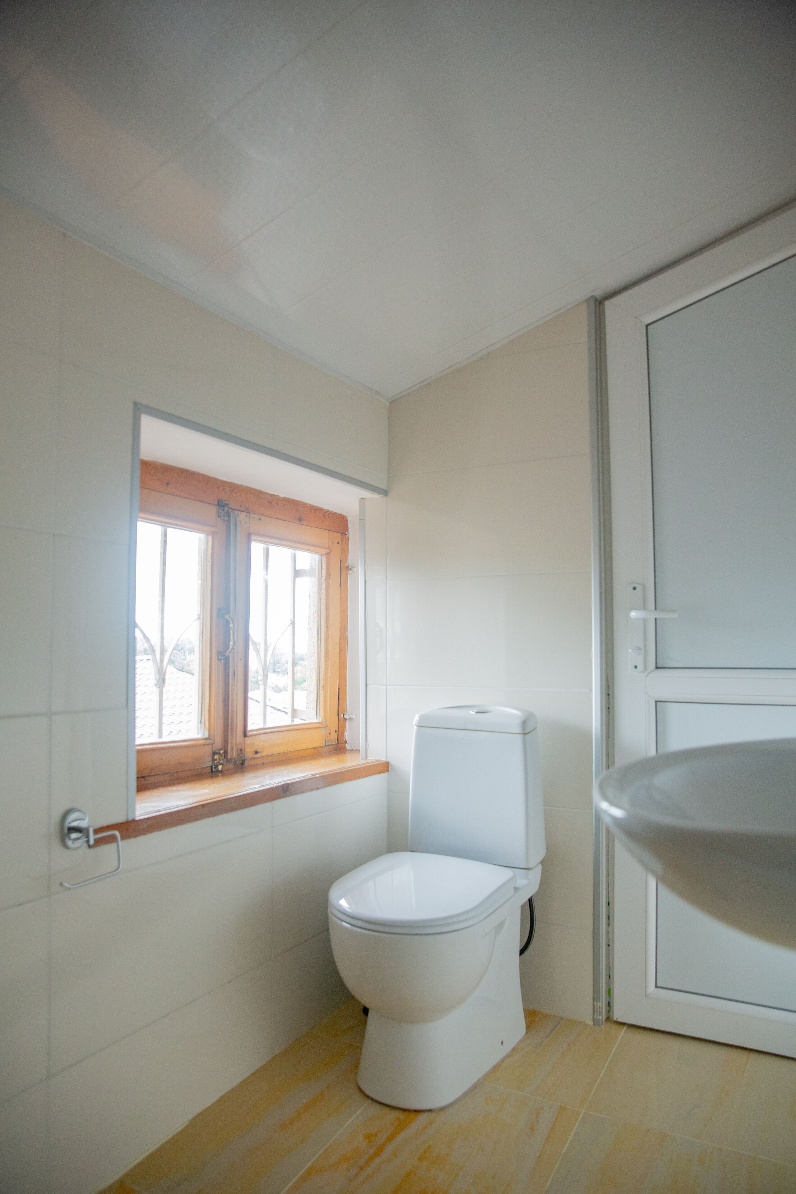 A small bathroom with a toilet, a window, and a door.