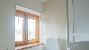 A small bathroom with a toilet, a window, and a door.
