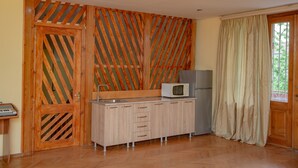 A compact kitchen with wooden cabinetry, a microwave, and a refrigerator.