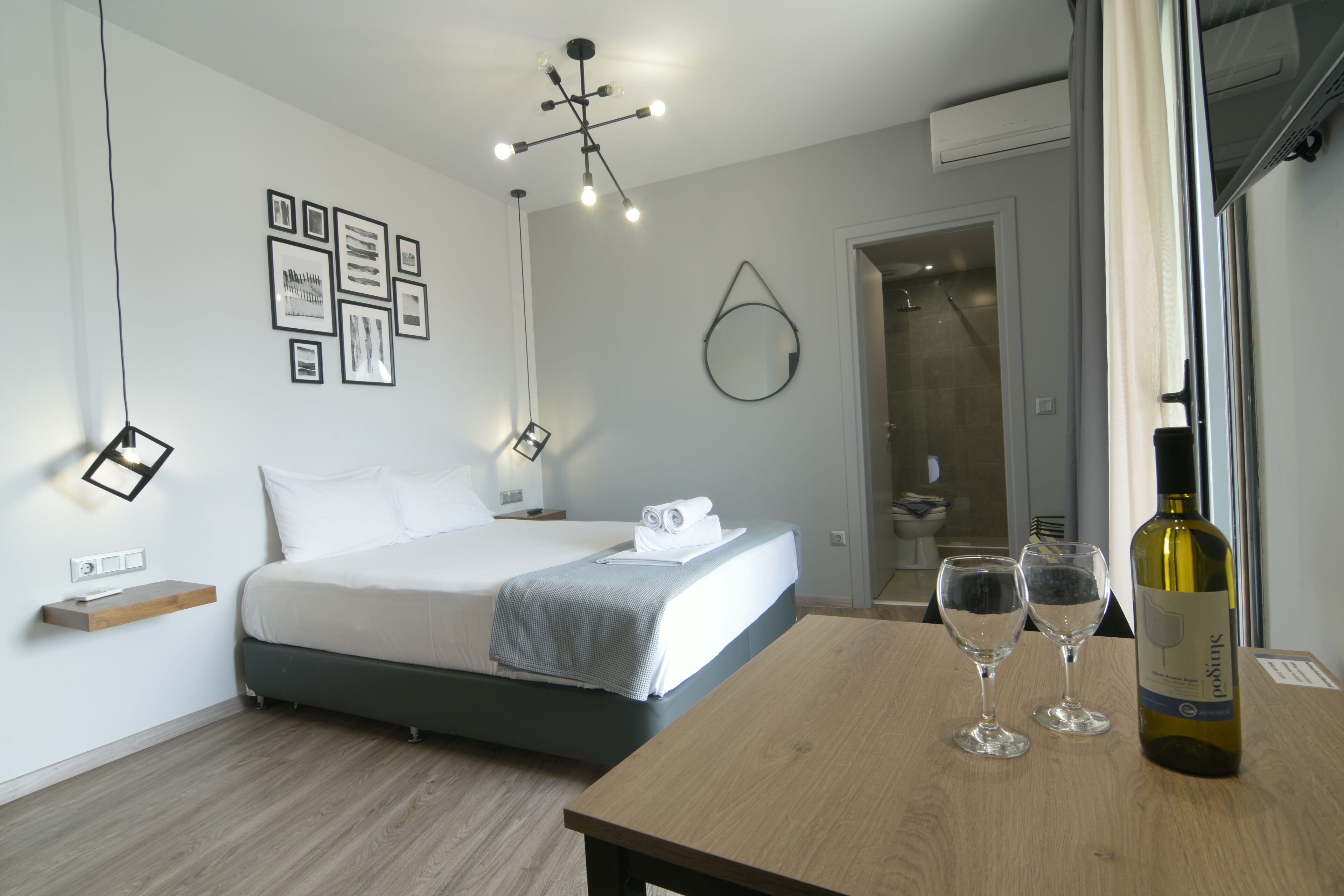 Een moderne slaapkamer met een bed, nachtkastje en een fles wijn.