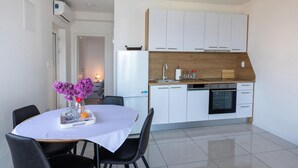 A modern kitchen with white cabinets, a wooden countertop, and a dining area with a table and chairs.