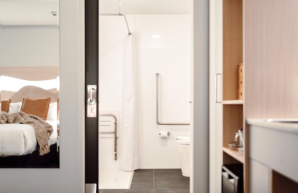 A modern bathroom with a shower, toilet, and grab bars.