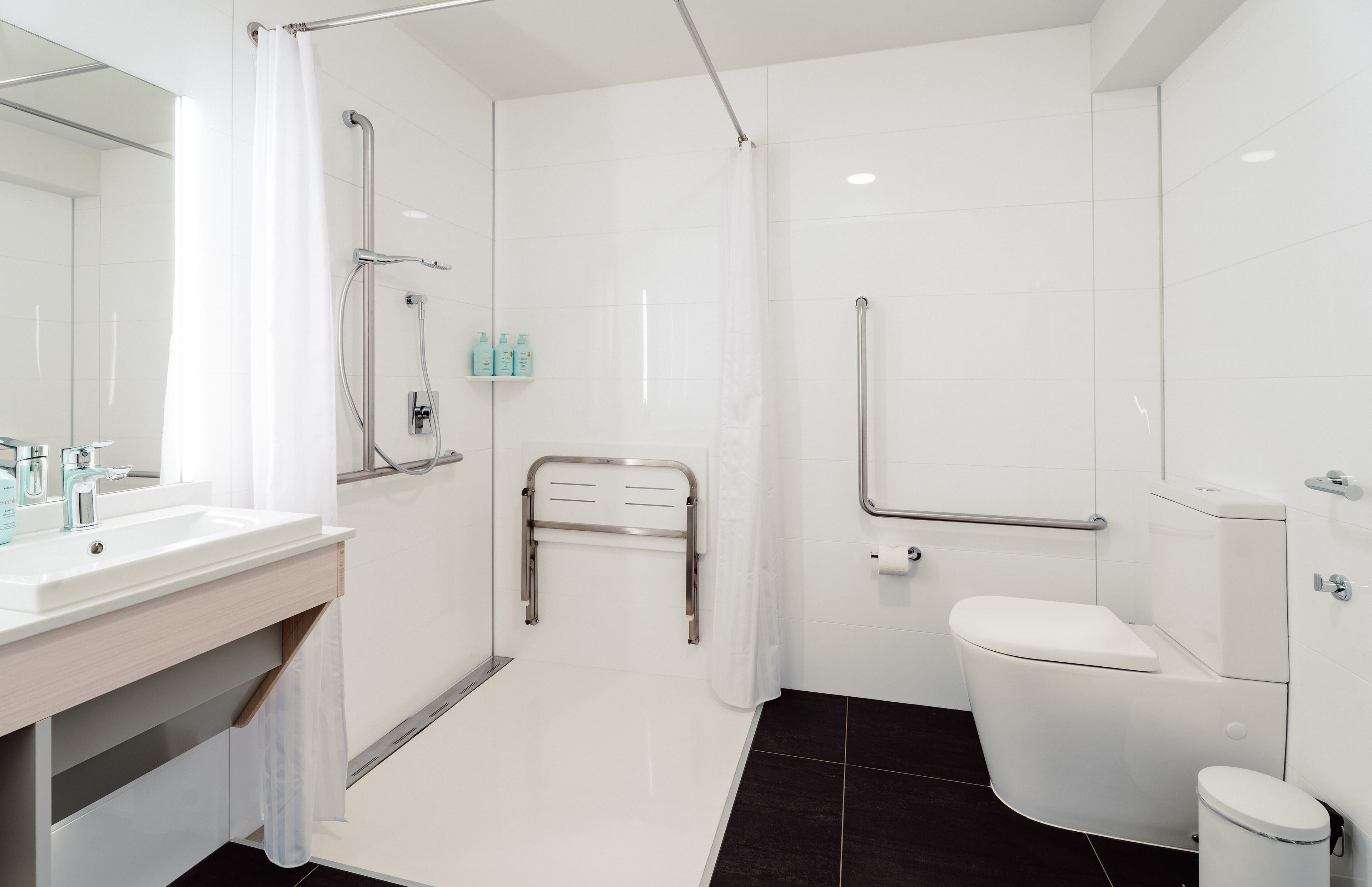 Een moderne badkamer met een wit wastafelmeubel, toilet en douchehoek.