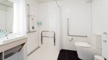 Een moderne badkamer met een wit wastafelmeubel, toilet en douchehoek.