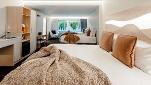 Een moderne hotelkamer met een groot bed, een bureau, een stoel en uitzicht op groen buiten het raam.