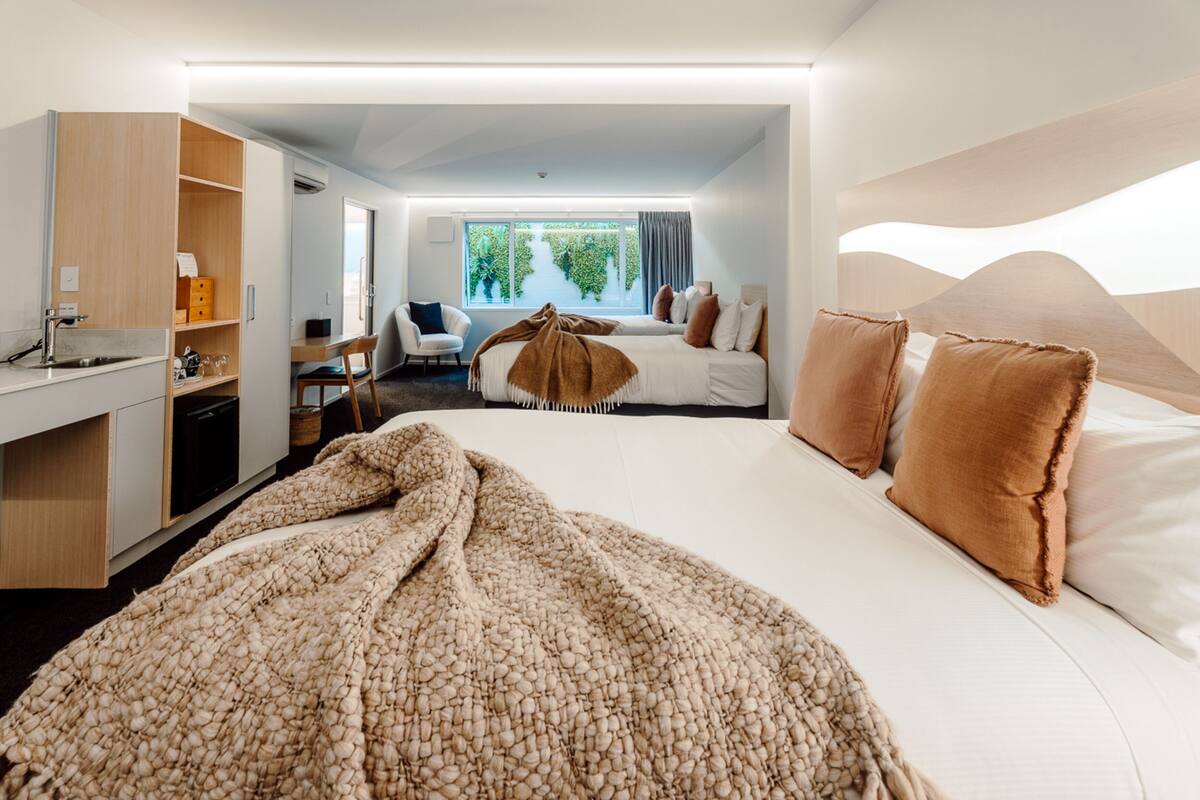 Een moderne hotelkamer met een groot bed, een bureau, een stoel en uitzicht op groen buiten het raam.