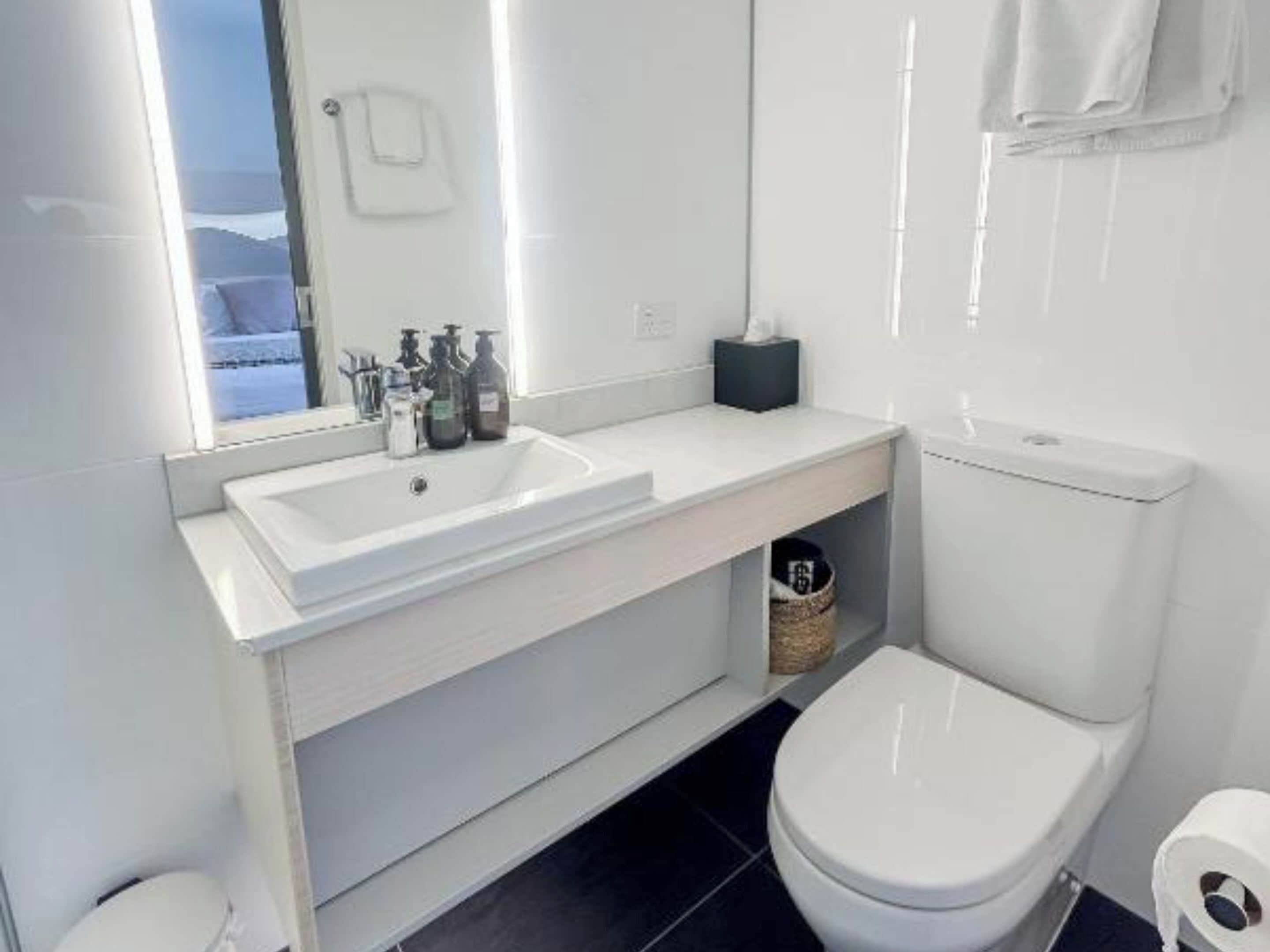 A modern bathroom with a white sink, mirror, and toilet.