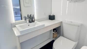 Ein modernes Badezimmer mit Waschbecken, Spiegel und Toilette in Weiß.