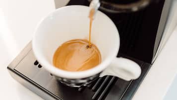 Una cafetera sirviendo café en una taza blanca.
