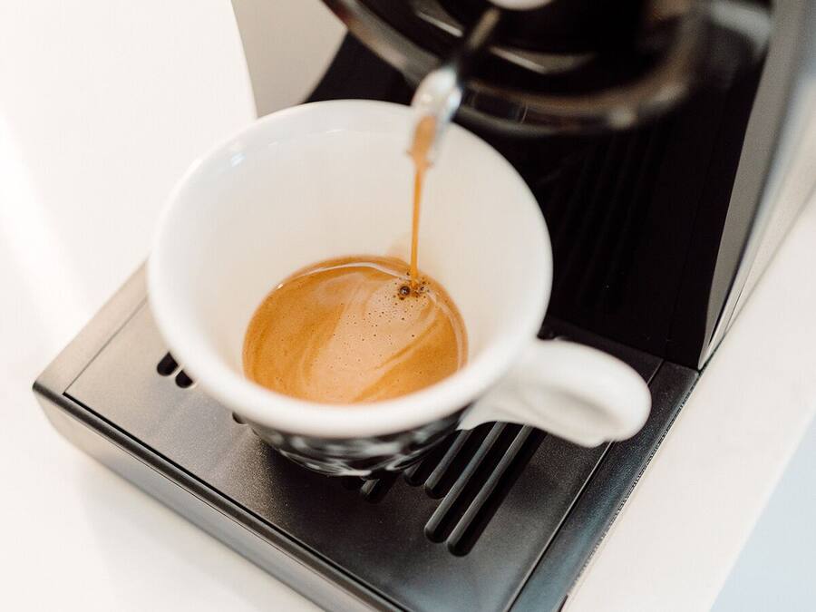 Eine Kaffeemaschine füllt Kaffee in eine weiße Tasse.