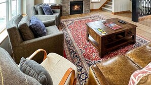 A cozy living room with a fireplace, comfortable seating, and a large window. - Charming Tri-Level Condo in Downtown McCall (McCall)
