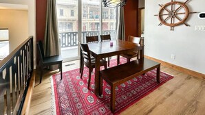 A dining area with a wooden table, chairs, and a red patterned rug. - Charming Tri-Level Condo in Downtown McCall (McCall)