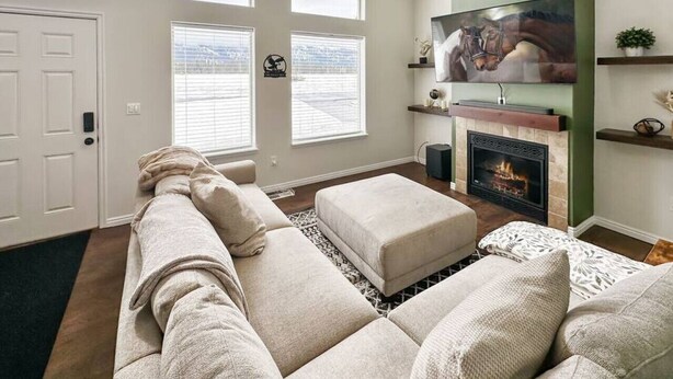A living room with a large sectional sofa, a fireplace, and a mounted TV. - Relaxing Mountain Hideaway | Near Tamarack Resort (Donnelly)