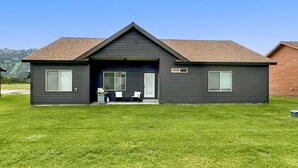 A modern two-story house with a dark exterior, a sloped roof, and a well-maintained lawn. - Relaxing Mountain Hideaway | Near Tamarack Resort (Donnelly)