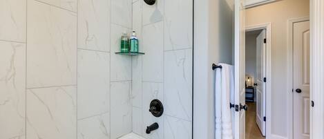 Ein Badezimmer mit einer Badewanne, einer Dusche und einem Glastablett mit Pflegeprodukten.