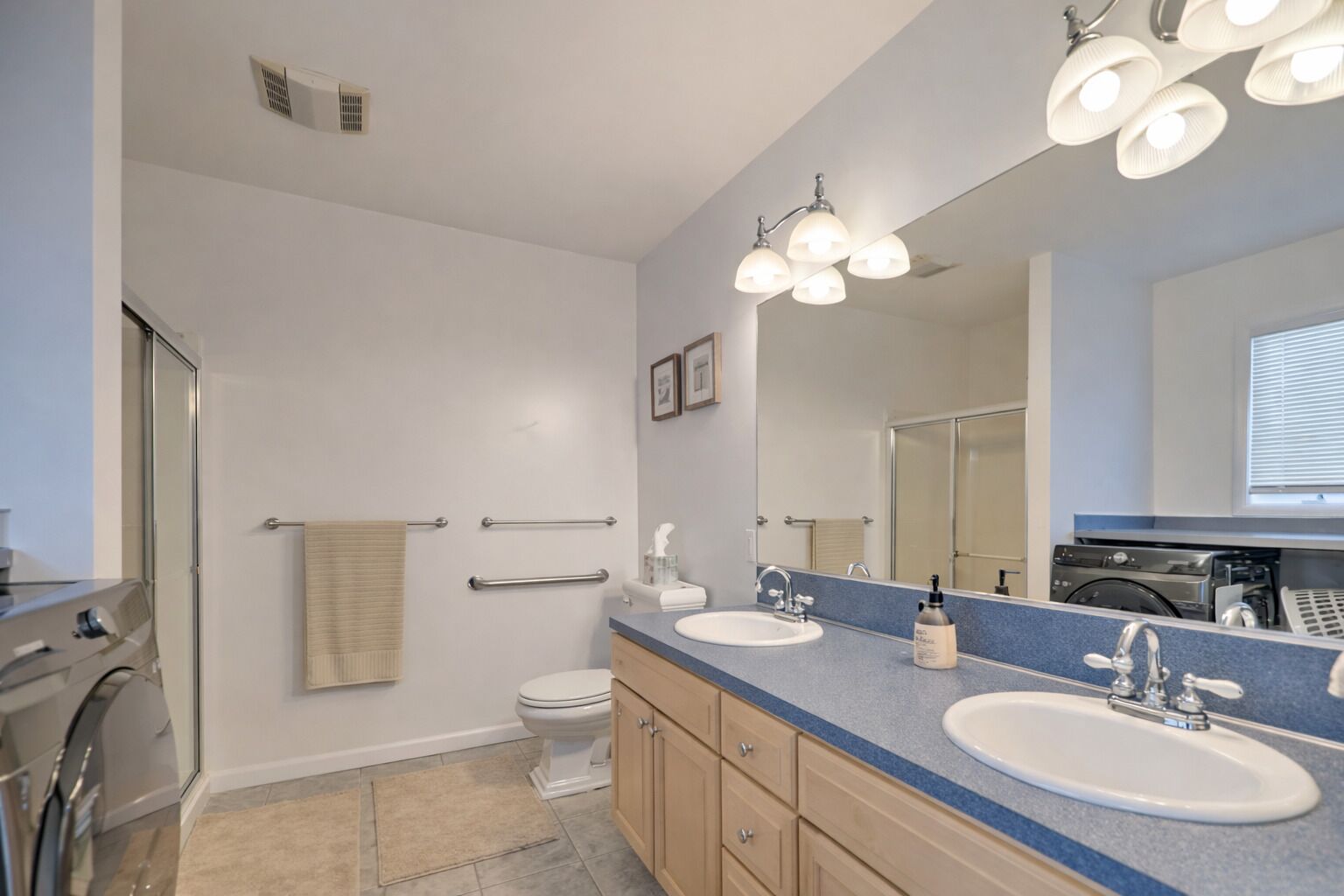 Bright, spacious bathroom with walk-in shower, double vanity sink and laundry