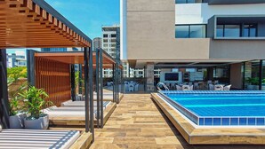 A rooftop pool area with a wooden pergola, lounge chairs, and a bar area. - Luxurious and cozy brand new apartment! (Santa Cruz de la Sierra)
