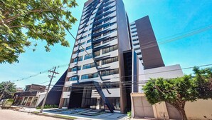 A modern multi-story building with a prominent entrance and a visible sign. - Luxurious and cozy brand new apartment! (Santa Cruz de la Sierra)