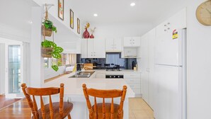 A modern kitchen with white cabinets, a central island, and wooden chairs.