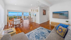 A spacious living area with a view of the ocean, a dining area, and a kitchen.
