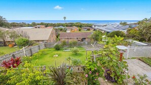 A residential area with houses, a grassy yard, and a view of the ocean.