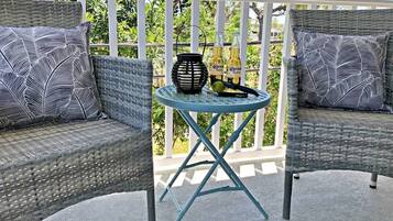A balcony with wicker furniture, a small round table, and two bottles of Corona Extra.