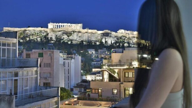 A view of a cityscape with a prominent ancient Greek temple on a hill, modern buildings in the foreground, and a person in the foreground. - Feel Athens Studios @ Monastiraki Free, Large Balcony with City view (Athens)