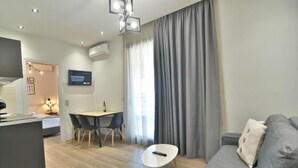 A modern living room with a grey sofa, a small white table, and a dining area with a table and chairs. - Feel Athens Studios @ Monastiraki Free, Large Balcony with City view (Athens)