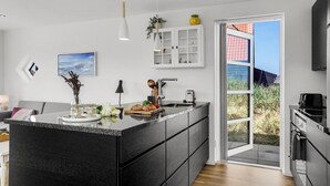 Eine moderne Küche mit Kochinsel, integriertem Backofen und großem Fenster mit Blick ins Freie.
