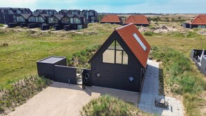 Ein modernes Haus mit einem geneigten Dach, großen Fenstern und einem gepflasterten Einfahrt.