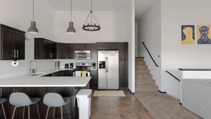 Una cocina moderna con armarios de madera oscura, electrodomésticos de acero inoxidable y una isla central con taburetes de bar.