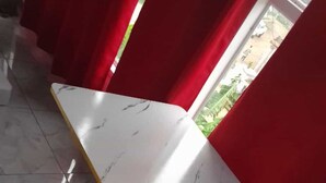 Une pièce avec une table blanche à motifs de marbre, une petite table ronde et des rideaux rouges.