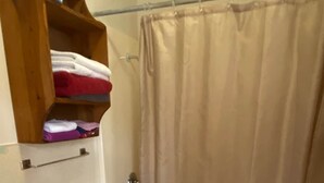 A bathroom with a toilet, sink, and shower curtain. - Cabin 3 - Reel and Trigger (Tom Township)
