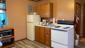 A compact kitchen with wooden cabinets, a white refrigerator, a stove, and a microwave. - Cabin 8 - Reel and Trigger (Tom Township)