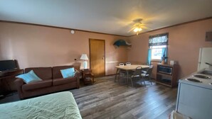 A compact room with a sofa, a dining table with chairs, a small kitchen area with a refrigerator, and a ceiling fan. - Cabin 8 - Reel and Trigger (Tom Township)