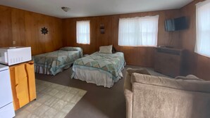 Une chambre avec deux lits, une télévision et une kitchenette.
